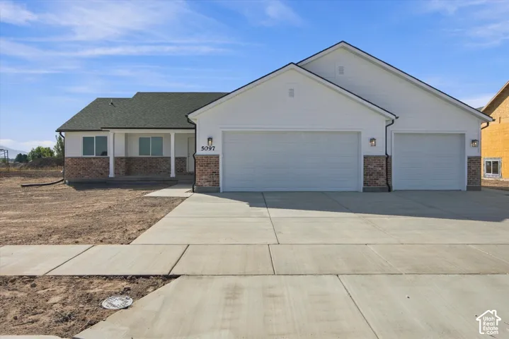 Contemporary exterior with brick and siding accents, a covered front porch, and an attached two-car garage