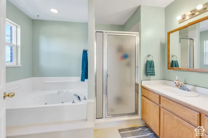 Built-in jetted tub, enclosed shower with frosted glass, wood-finish vanity, single basin sink