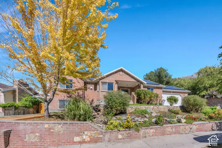 Brick exterior featuring an attached garage, covered entryway, and solar panels