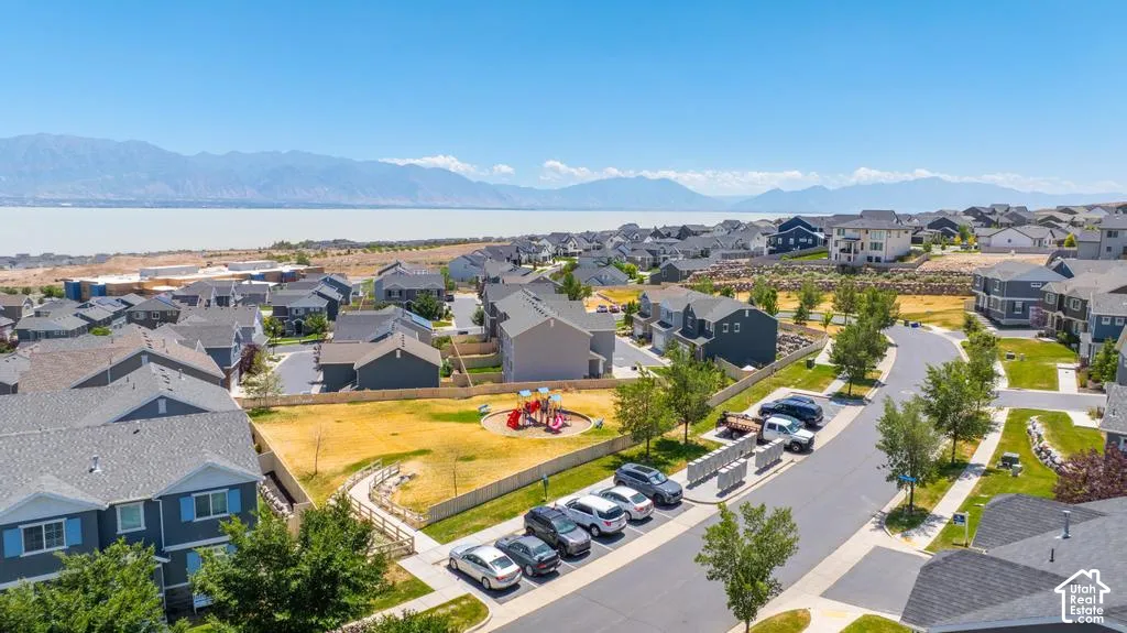 Residential community featuring a central park with playground, paved streets, and a prominent water body with mountain backdrop