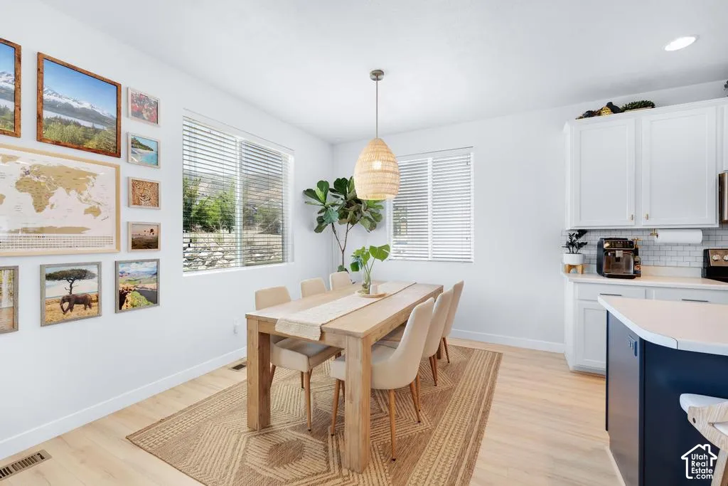 Light wood-finish flooring, white walls, and built-in white cabinetry with a tile backsplash