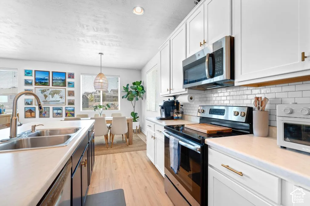 Kitchen featuring white cabinetry, light countertops, a stainless steel sink, and wood-finish flooring