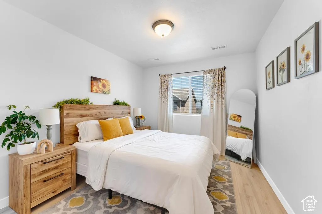 Light wood-finish flooring, recessed window with blinds, overhead flush-mount lighting, and light-toned walls