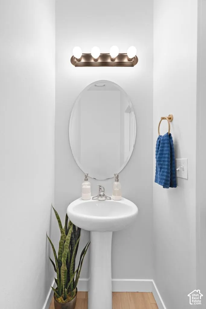 Pedestal sink with chrome faucet, oval mirror, and a bronze-finish four-light vanity fixture