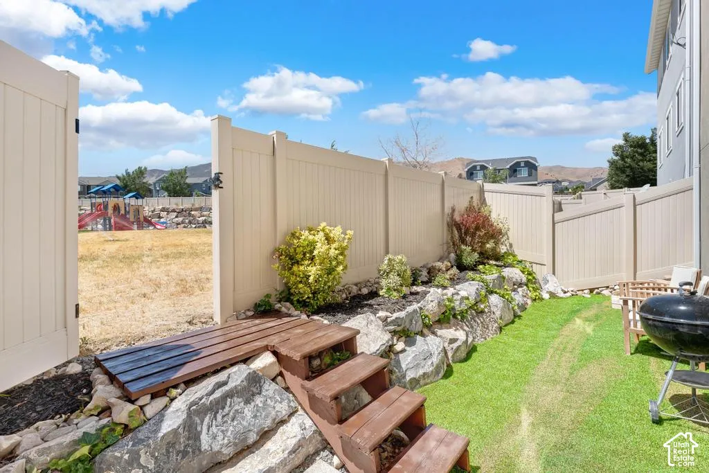 Private fenced yard with natural rock landscaping and stepped wood pathway