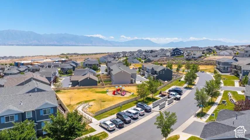 Residential community featuring a central park with playground, paved streets, and a prominent water body with mountain backdrop