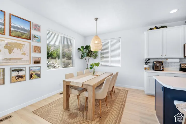Light wood-finish flooring, white walls, and built-in white cabinetry with a tile backsplash