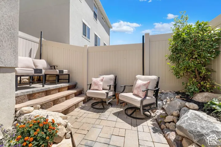 Paved patio with decorative rock landscaping, privacy fencing, and tiered retaining wall steps