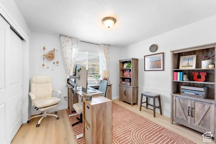 Light wood-finish flooring, white walls, built-in shelving, and a window with blinds