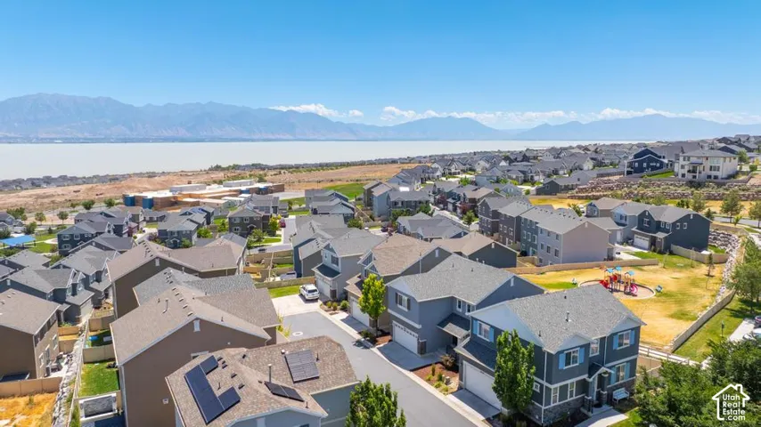 Residential community with a playground, mature trees, and mountainous scenery