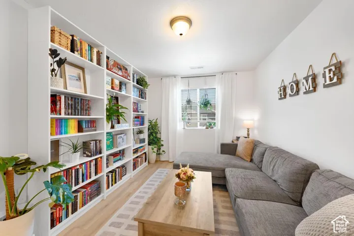 Integrated wall-to-wall shelving, wood-finish flooring, recessed lighting, and a single window with blinds