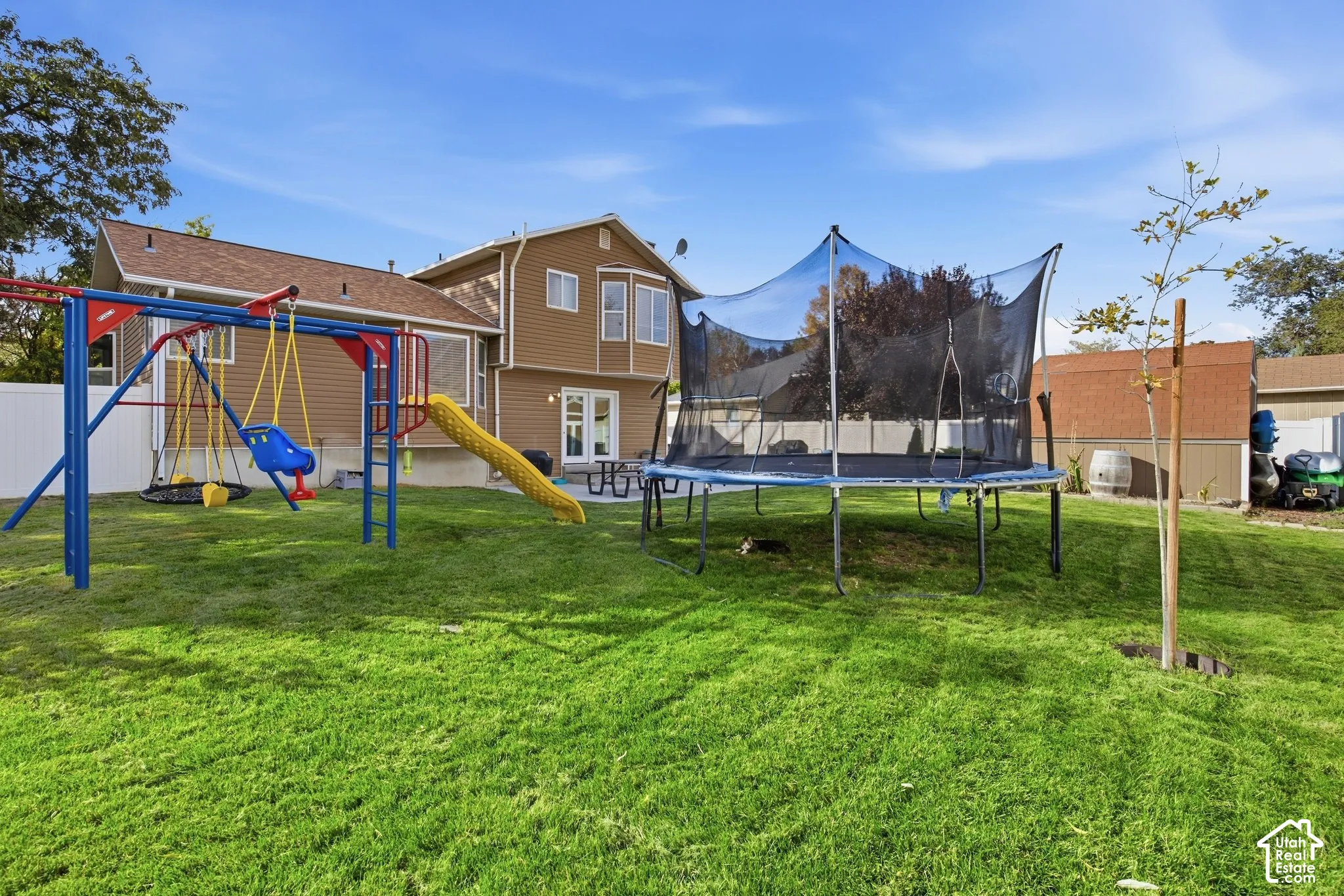 Expansive green lawn with a white privacy fence