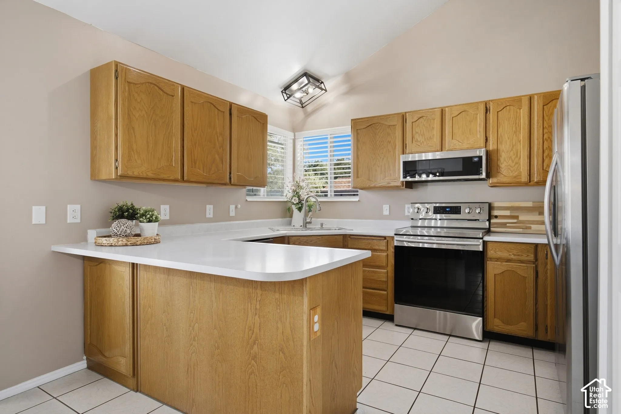 Kitchen featuring wood cabinetry, stainless steel appliances, white countertops, and vaulted ceilings