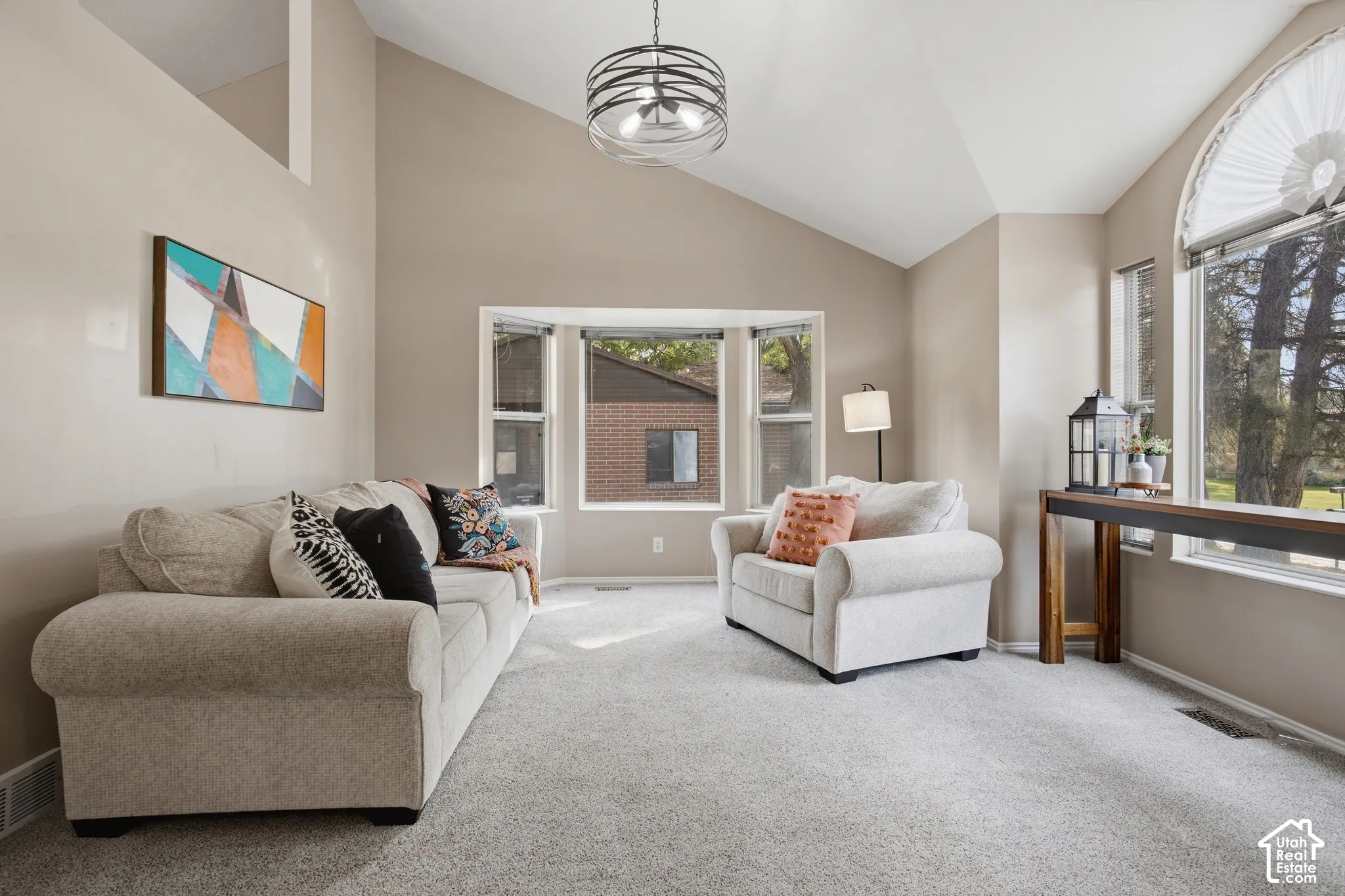 Vaulted ceilings, bay window, arched window, textured carpeting, and neutral paint tones