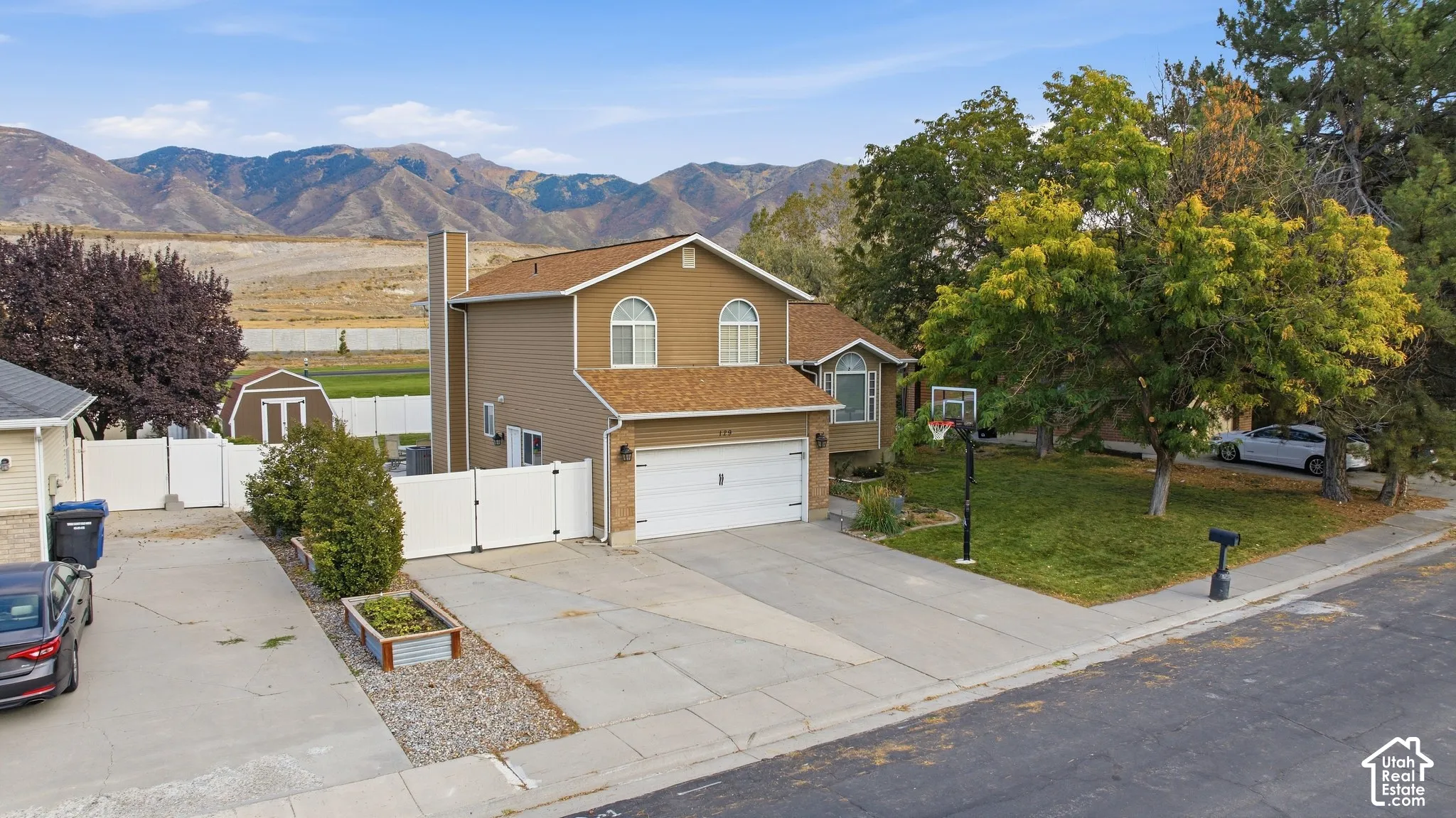 Two-story residence with a two-car garage, mature front yard trees, and a mountain backdrop