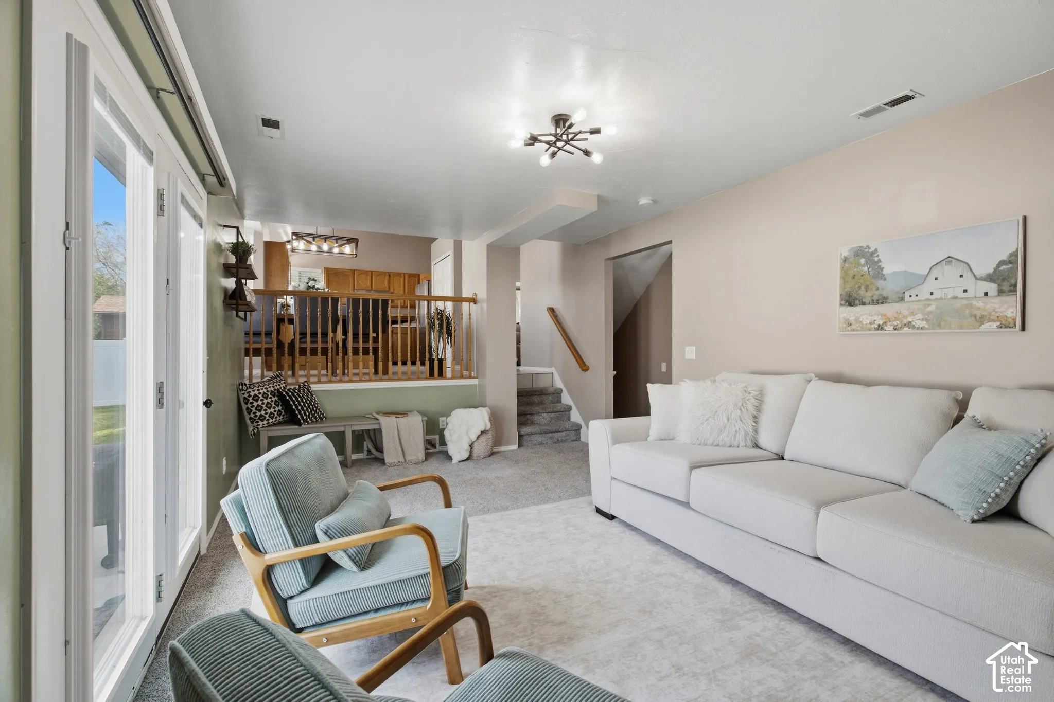 Carpeted flooring throughout, white framed glass French doors, and a decorative ceiling light fixture