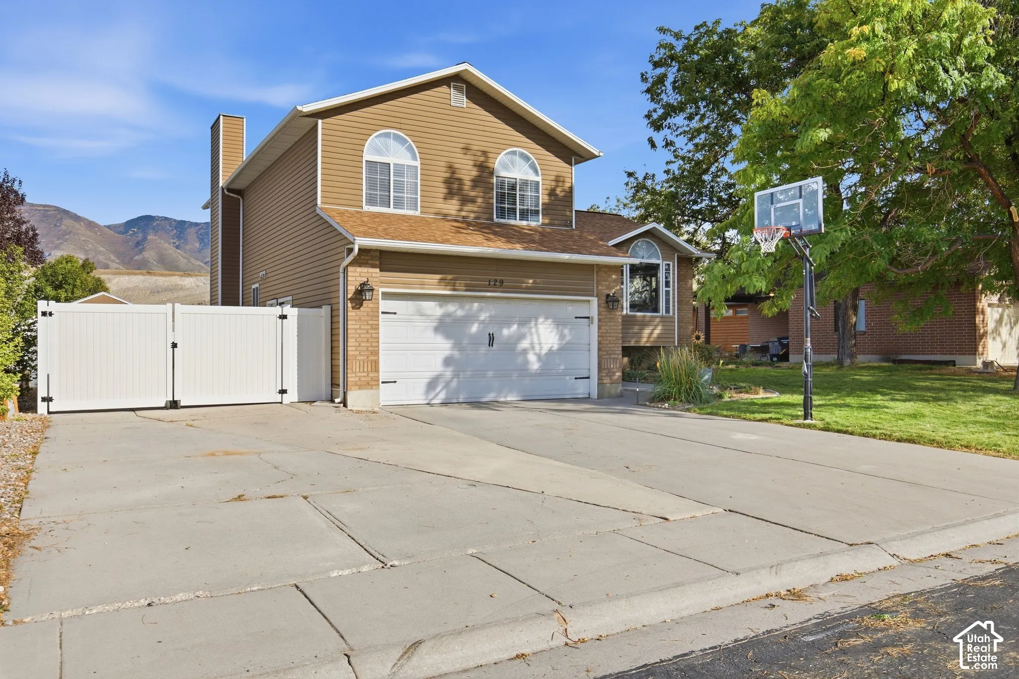Two-story residence featuring a two-car garage, brick and siding exterior, and arched windows