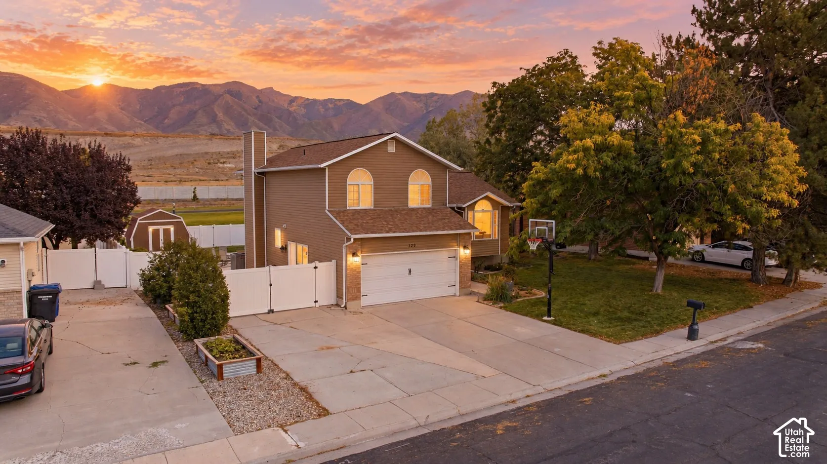 Two-story residence with a two-car garage, mature front yard trees, a driveway, and a backyard shed
