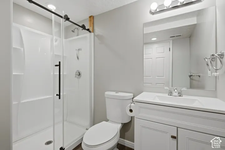White vanity with recessed paneling and chrome hardware, a white countertop with an integrated sink, a rectangular mirror, and a chrome light fixture with three bulbs
