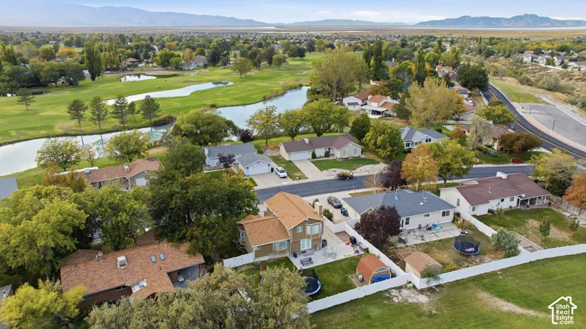 Residential neighborhood featuring mature trees, a golf course with water features, and distant mountain scenery