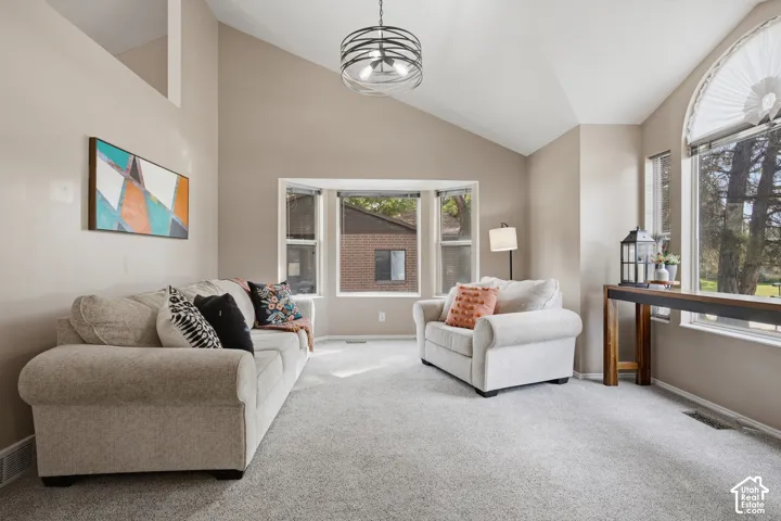 Vaulted ceilings, bay window, arched window, textured carpeting, and neutral paint tones