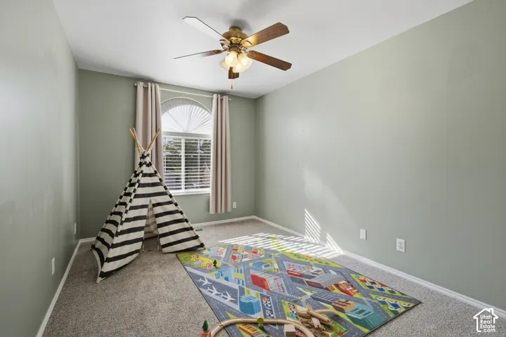 Carpeted room with a ceiling fan, recessed lighting, and a window with an arched transom
