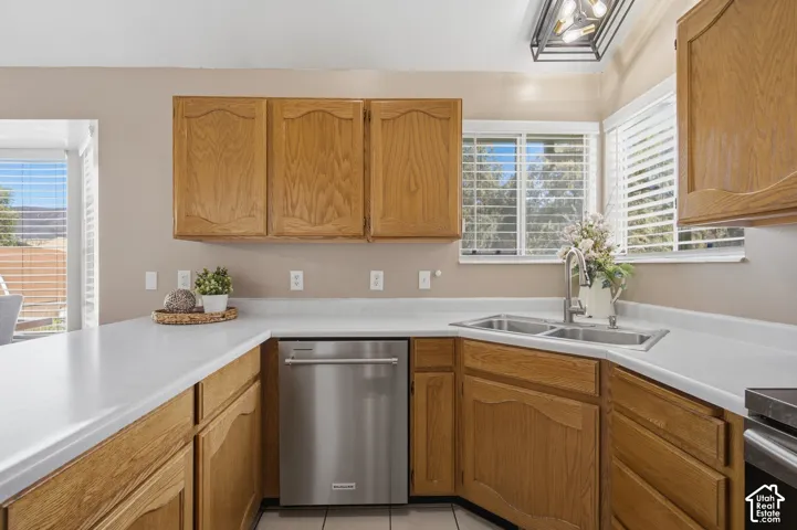 Kitchen featuring wood cabinetry, white countertops, a stainless steel dishwasher, and a double basin sink with a chrome faucet