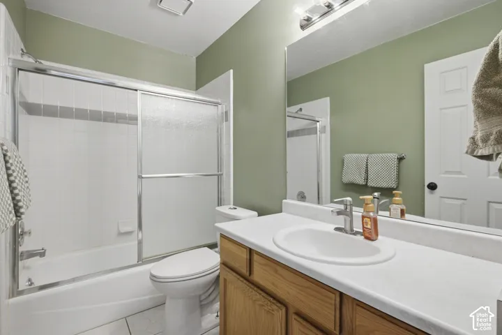 Tub/shower combination with sliding glass doors, single vanity with integrated sink, wood-finish cabinetry, and wall-mounted mirror