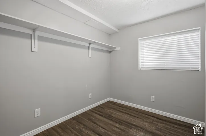 Neutral wall paint, wood-finish flooring, built-in shelving, window with blinds, and white trim