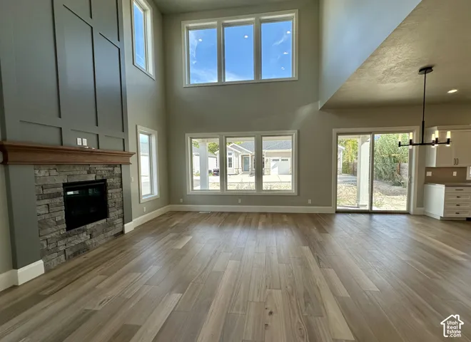 Two-story living area with a floor-to-ceiling stone fireplace, wood-finish flooring, and multiple windows
