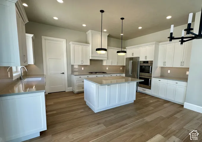 Kitchen featuring white cabinetry, hardwood flooring, a central island with Quartzite, recessed lighting, and stainless steel Bosch appliances
