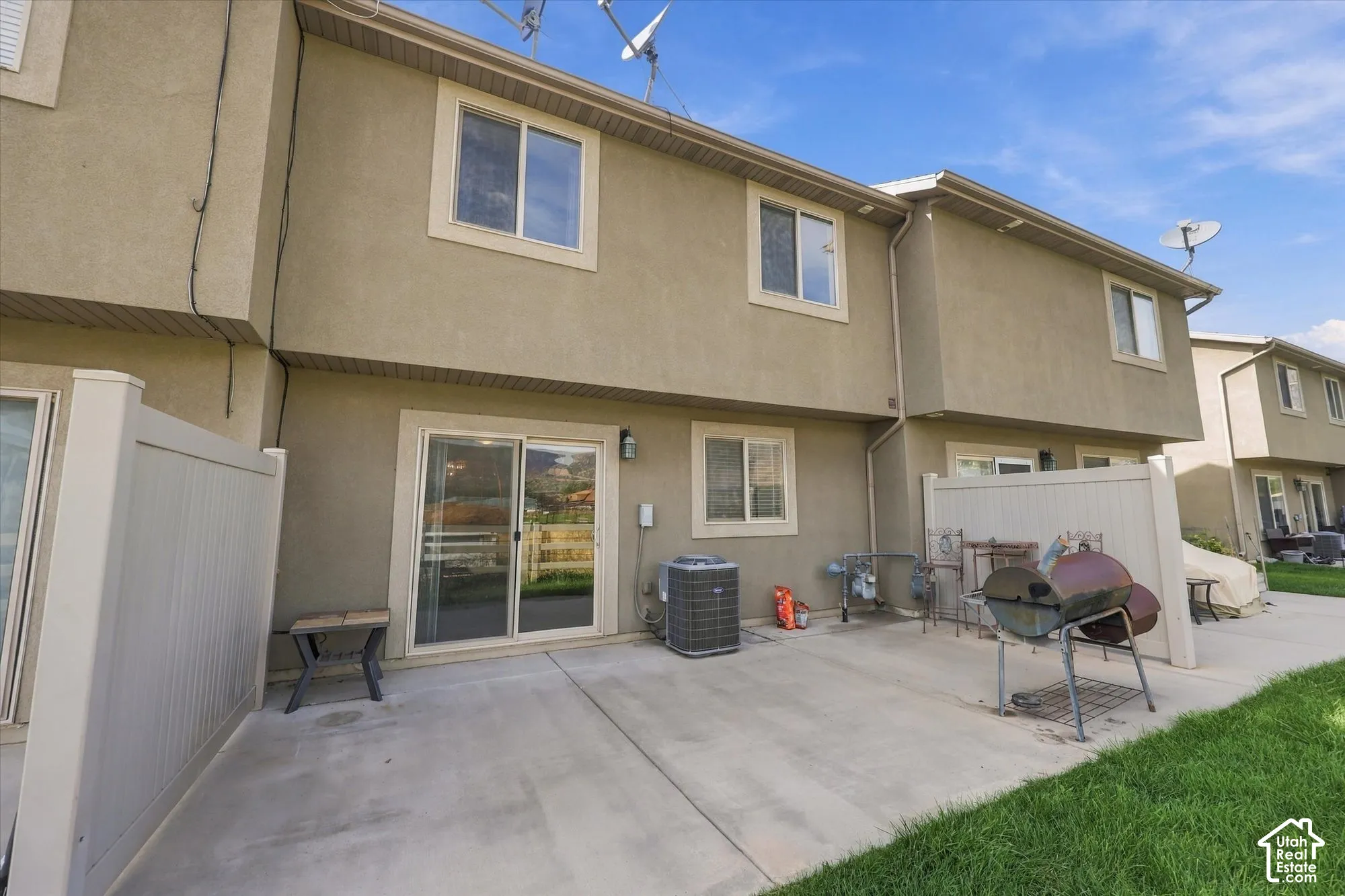 Rear patio with a sliding glass door and vinyl fencing