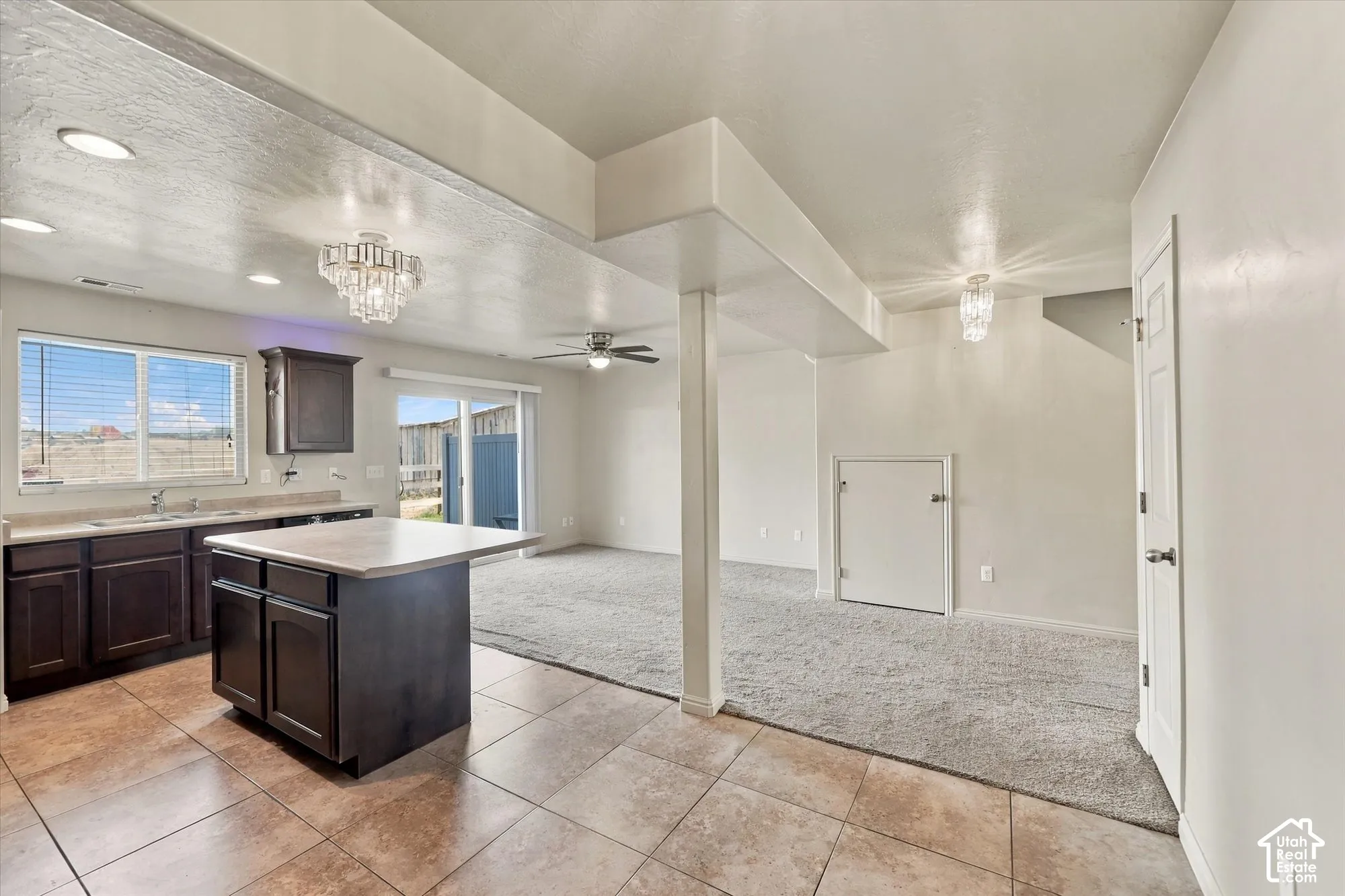 Tile flooring, kitchen island with countertop, dark wood-finish cabinetry, recessed lighting, and a sliding glass door