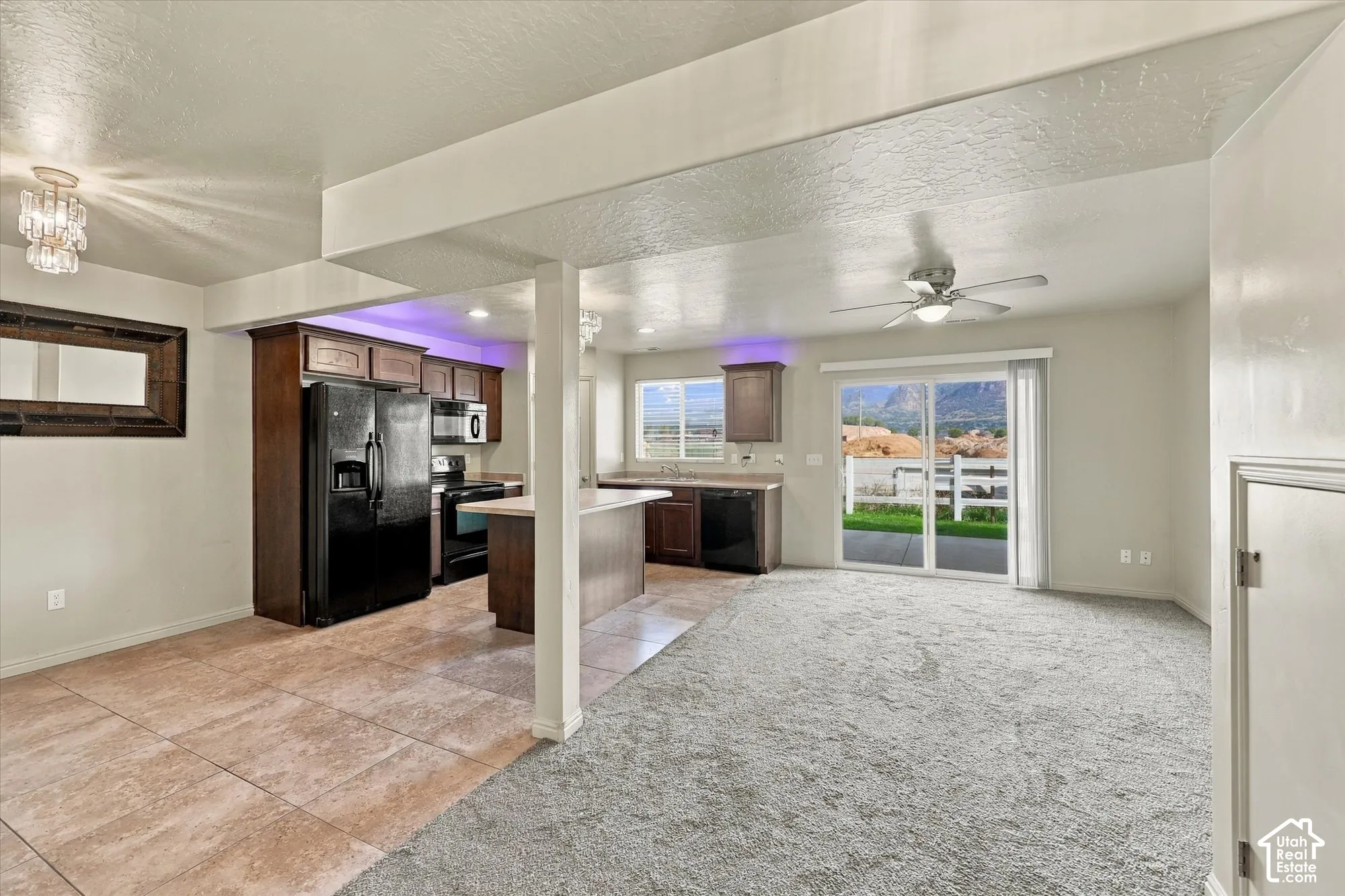 Kitchen featuring wood-finish cabinetry, black appliances, and a peninsula with countertop seating