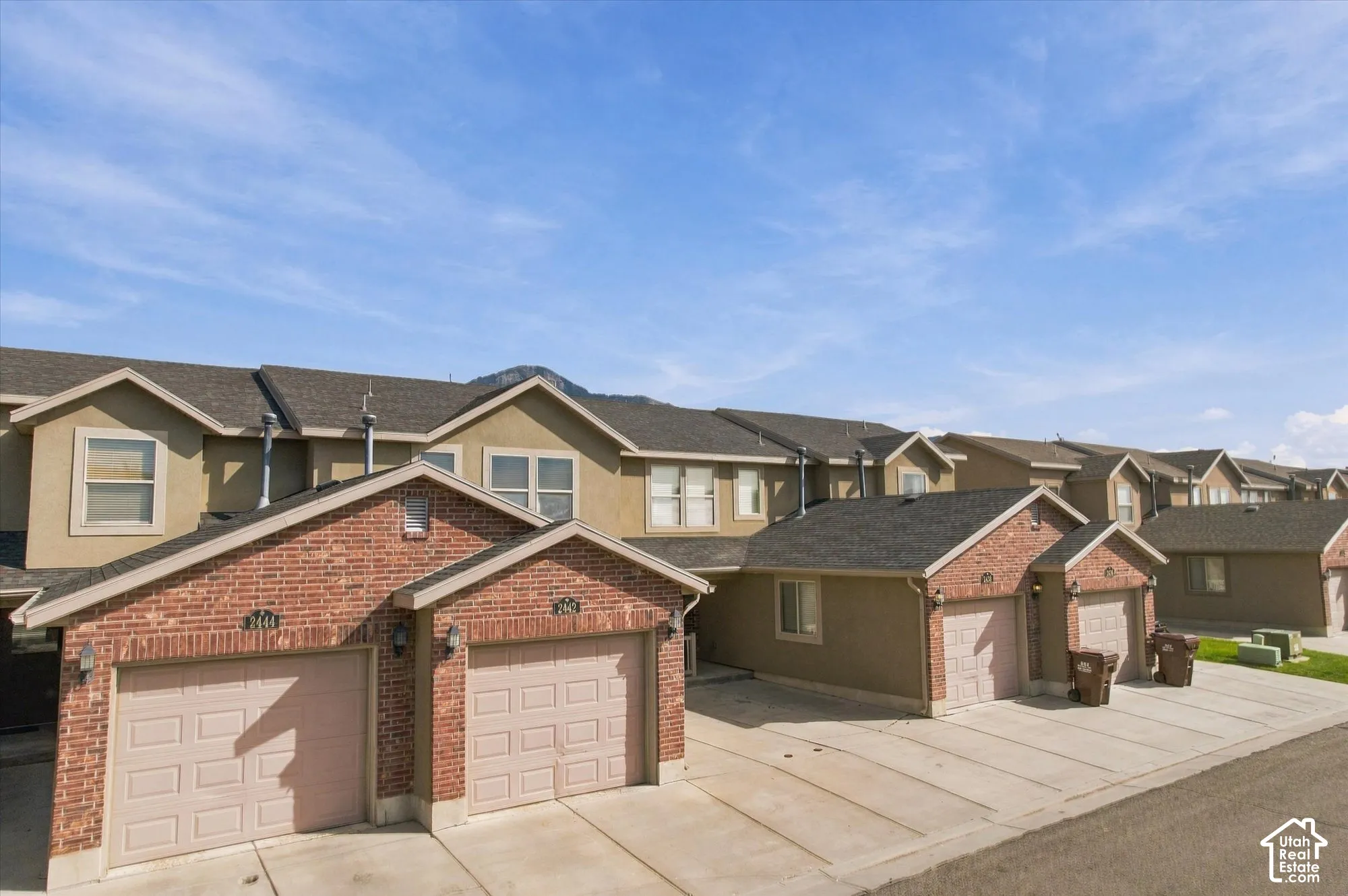 Attached garages with panel doors, brick accents, and stucco siding