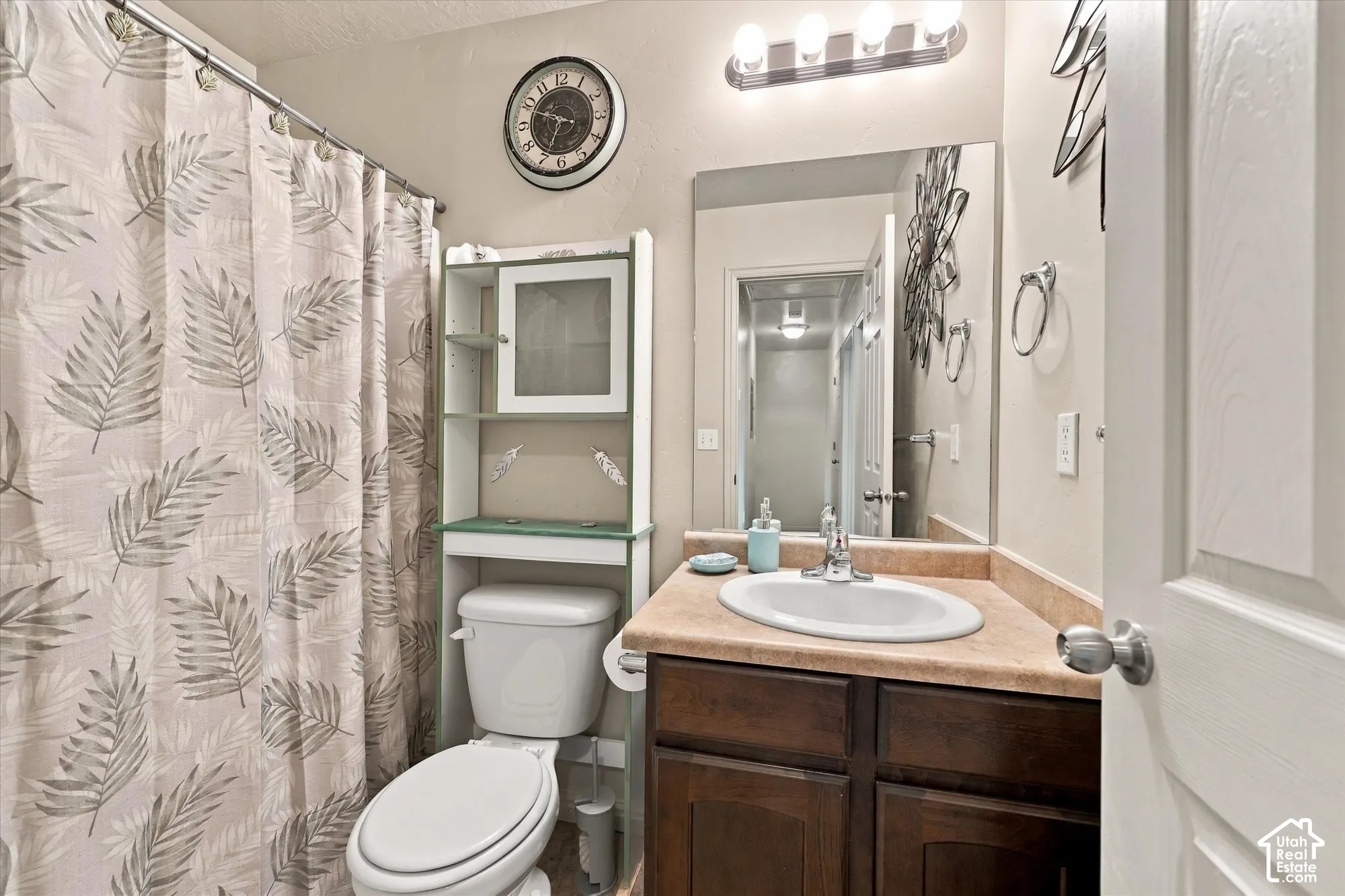 Bathroom featuring a wood-finish vanity with an oval sink, an expansive mirror, and overhead lighting