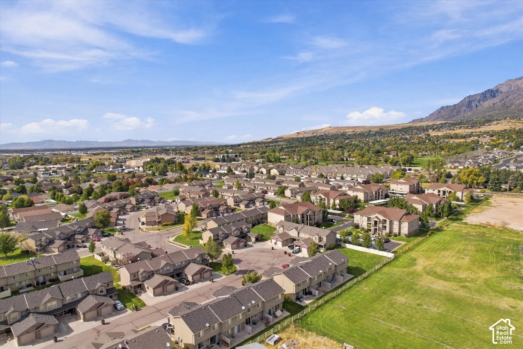 Community setting with diverse residential structures, expansive green spaces, and a mountainous backdrop