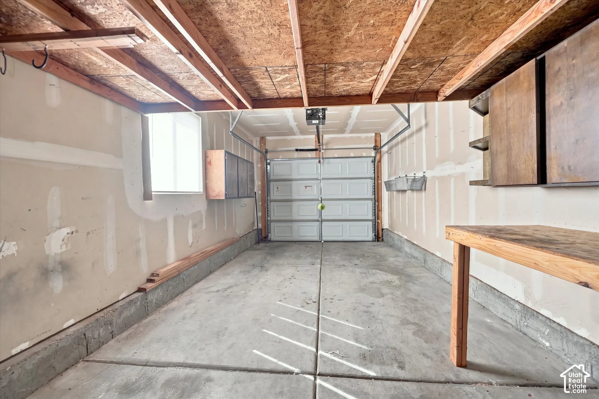 Concrete flooring with exposed ceiling joists, overhead garage door, and a built-in window