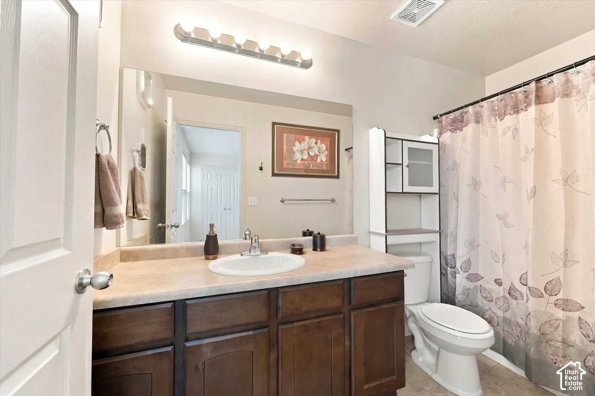 Vanity with wood-finish cabinetry and light-colored countertop