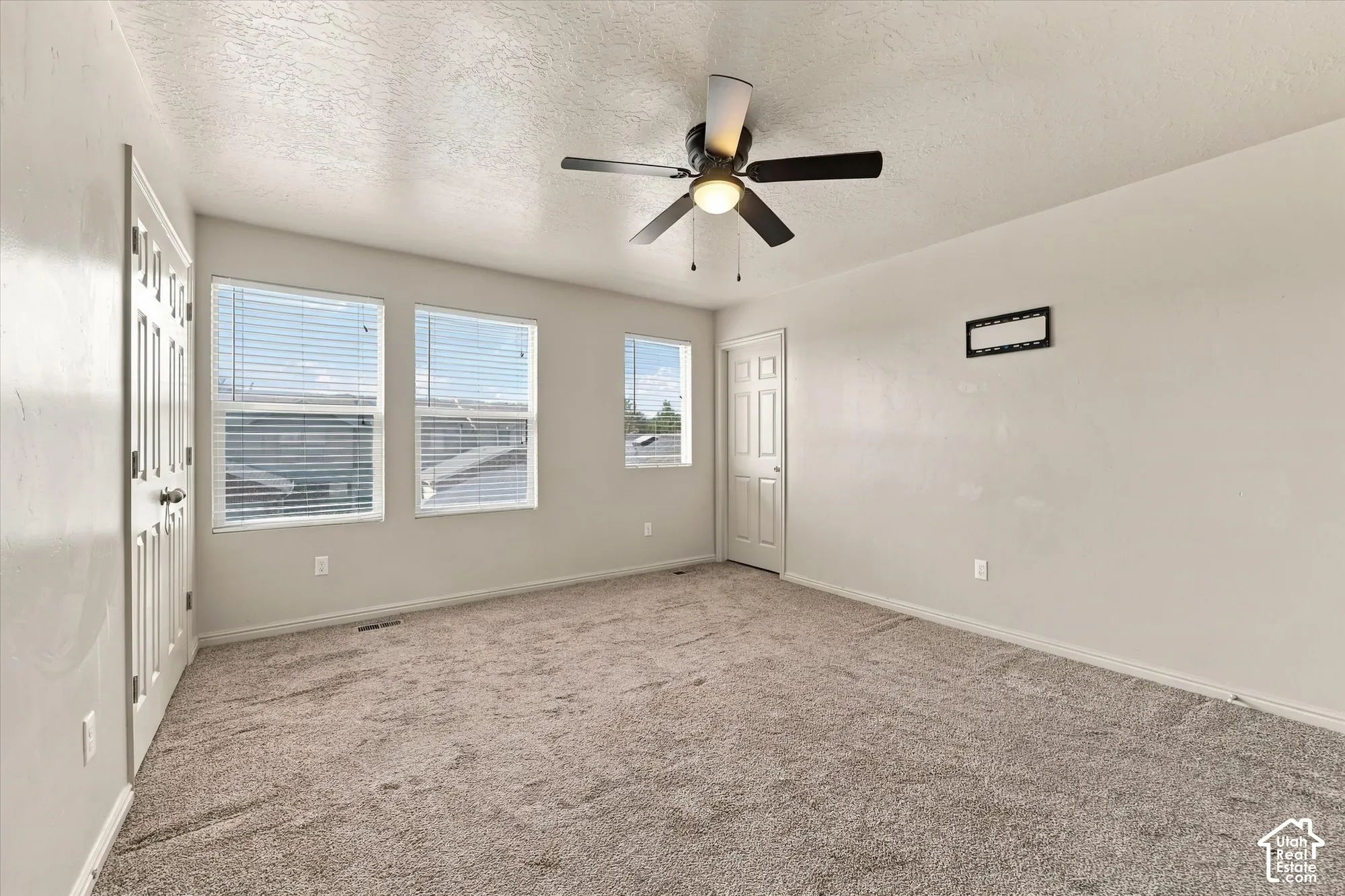 Recessed lighting, ceiling fan with integrated lighting, three windows with blinds, light-colored walls, and neutral-toned carpet