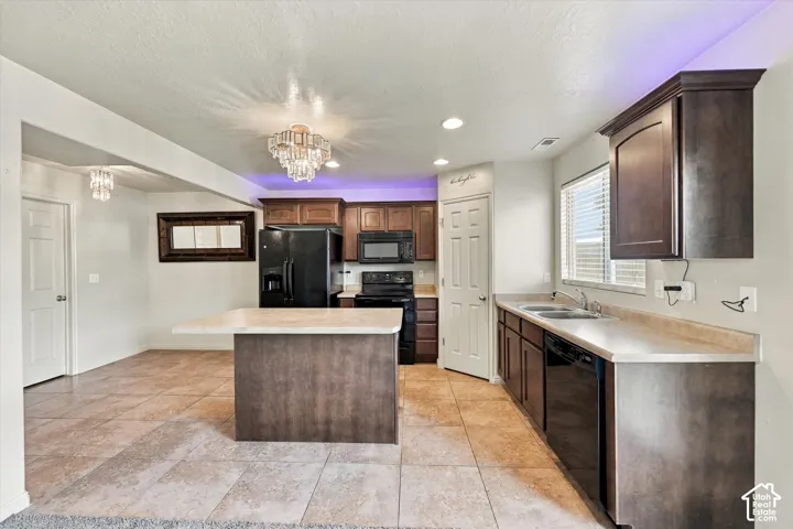 Kitchen featuring an island with countertop seating, dark wood-finish cabinetry, black appliances, and tile flooring