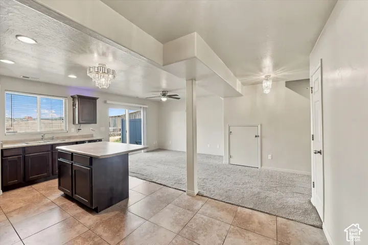 Tile flooring, kitchen island with countertop, dark wood-finish cabinetry, recessed lighting, and a sliding glass door