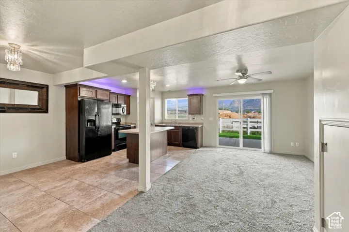 Kitchen featuring wood-finish cabinetry, black appliances, and a peninsula with countertop seating