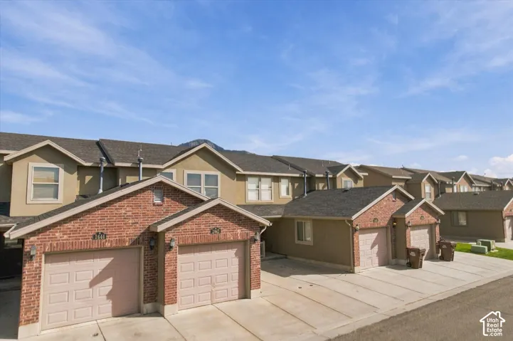 Attached garages with panel doors, brick accents, and stucco siding