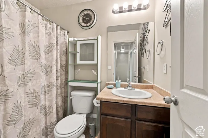 Bathroom featuring a wood-finish vanity with an oval sink, an expansive mirror, and overhead lighting
