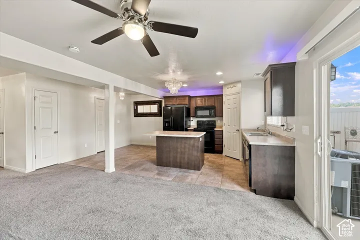 Open-concept living space featuring a ceiling fan, sliding glass door, kitchen island, and a full suite of black appliances