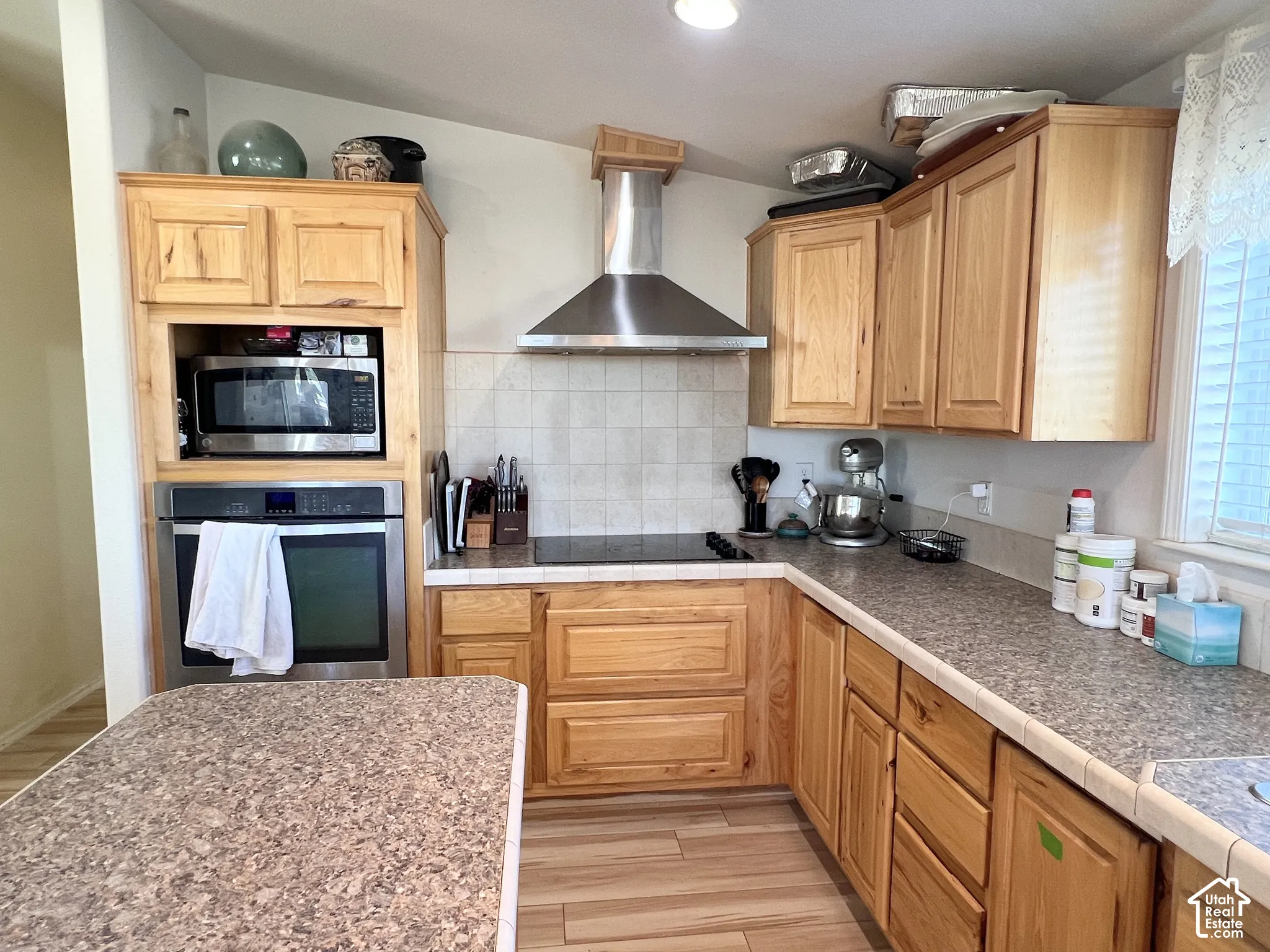 Hardwood cabinetry, stainless steel appliances, tile backsplash, laminate countertops, and wood-finish flooring