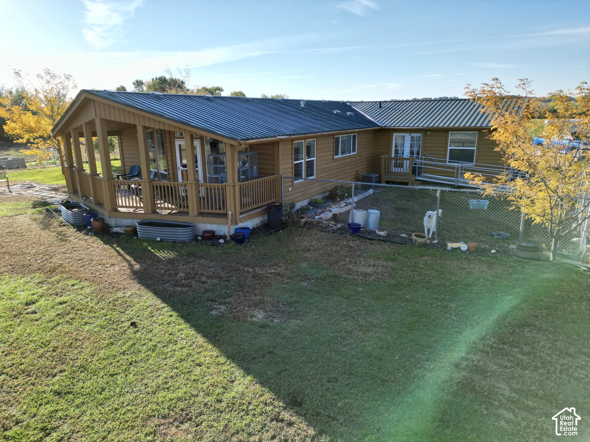 Wood-sided exterior featuring an enclosed porch, metal roof, and a fenced yard