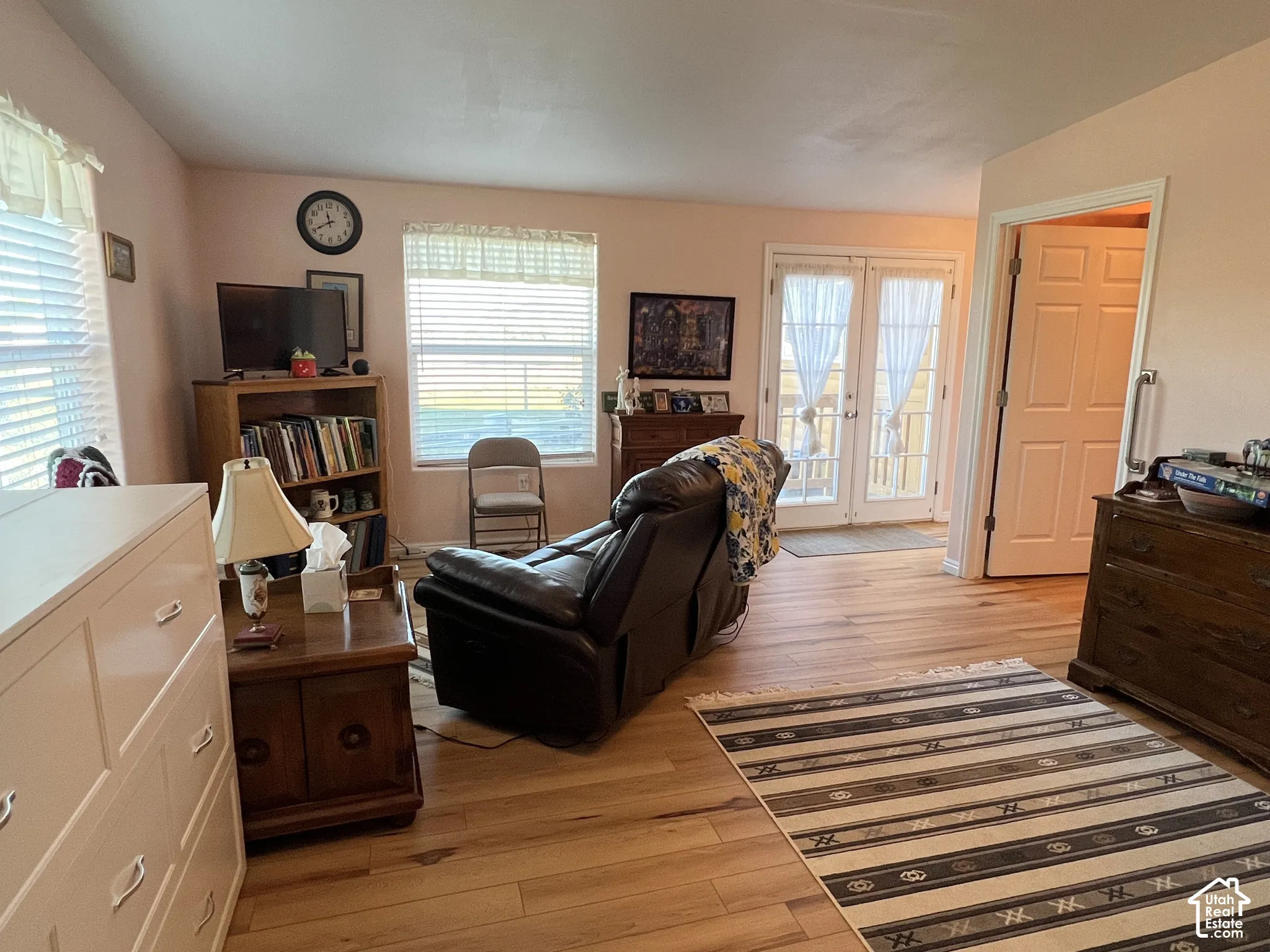 Wood-finish flooring throughout, multiple windows with blinds, and double patio doors