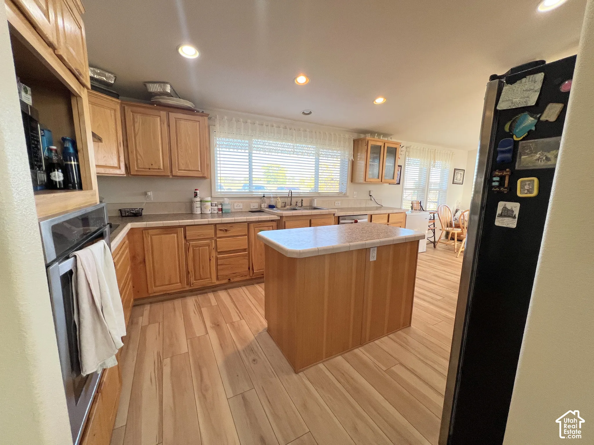 Kitchen featuring wood-finish flooring, recessed lighting, wood cabinetry, a built-in oven, and a center island with a tile countertop